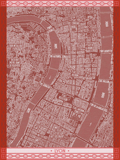 A map-style print of Lyon, France, on a cotton dishtowel in a muted dusty rose and white color scheme with a decorative red border and the word "LYON" at the bottom.