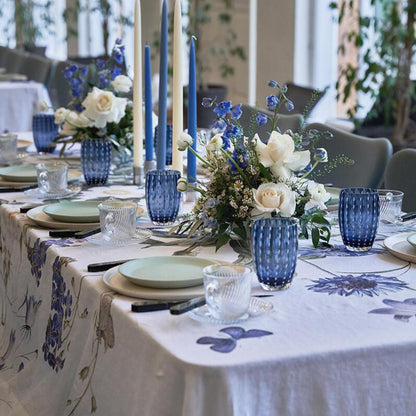 Elegant table setting with the blue flower garden linen tablecloth,  blue and white floral arrangements, candles, and glassware.