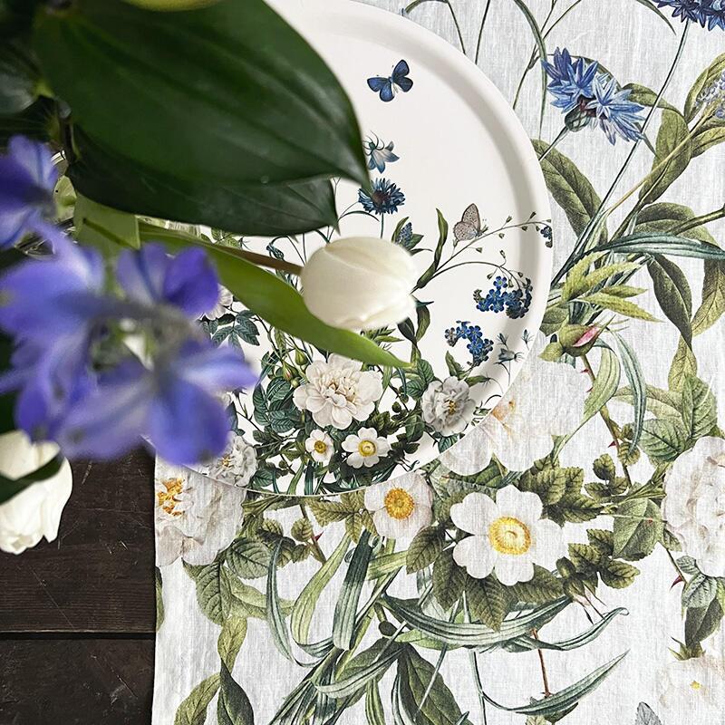 A closeup of the Blue Flower Garden table runner with a white flowers and green leaves
