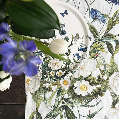 A closeup of the Blue Flower Garden table runner with a white flowers and green leaves