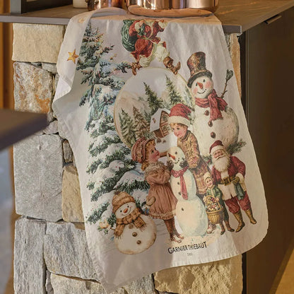 Decorative kitchen towel with a Christmas-themed design featuring children and snowmen,  Santa, and a fir tree hanging on a stone wall.