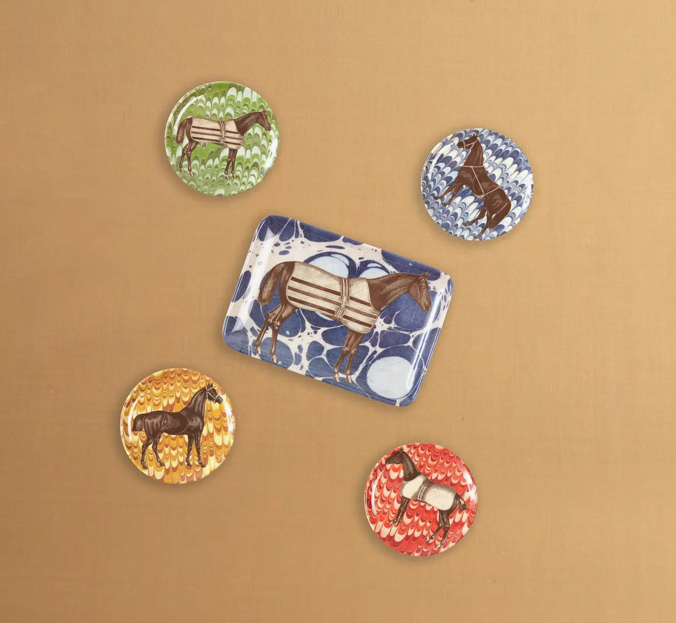 Set of four round melamine coasters arranged around a horse tray. Each coaster features an elegant brown horse illustration set against a vibrant, marbled background pattern in shades of mustard yellow, ocean blue, sage green, and brick red.
