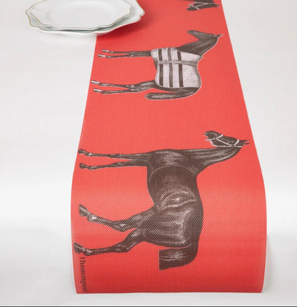 Red vinyl table runner with brown horse illustrations on a white surface