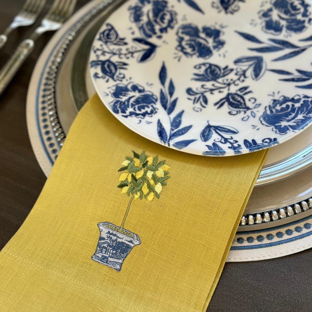 Yellow embroidered lemon topiary linen towel styled in between a stack of plates.