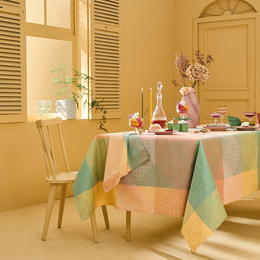 Mille Empreintes Pastel Jacquard Tablecloth in pastel cotton featuring geometric and plaid-inspired motifs, styled on a dining table in a yellow-walled room.