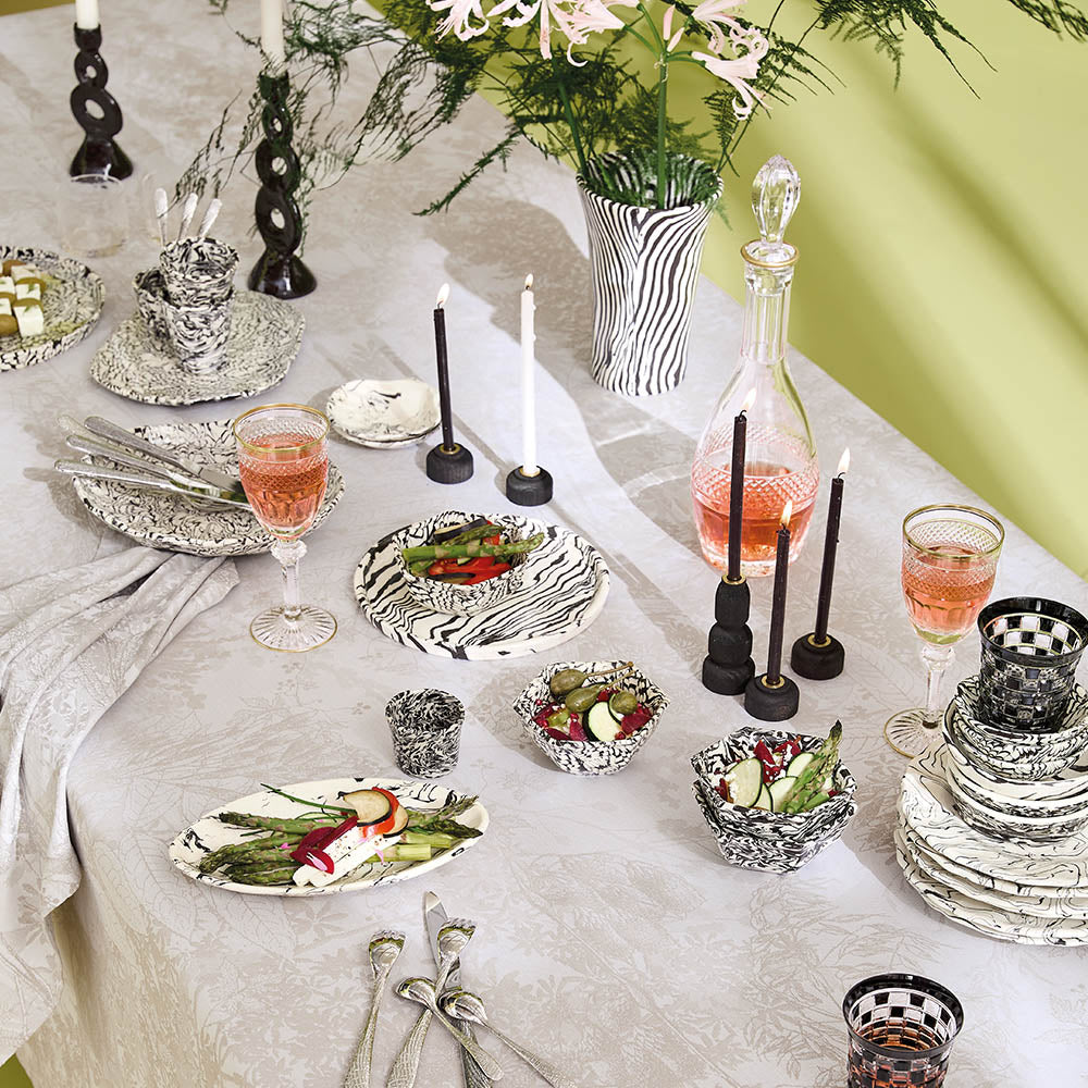 Elegant table setting on the Mille Esprit Jardins Chanvre Coated Tablecloth, cream botanical floral cotton jacquard, black and white striped dinnerware and candles.