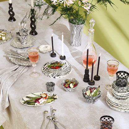 Elegant table setting on the Mille Esprit Jardins Chanvre Coated Tablecloth, cream botanical floral cotton jacquard, black and white striped dinnerware and candles.