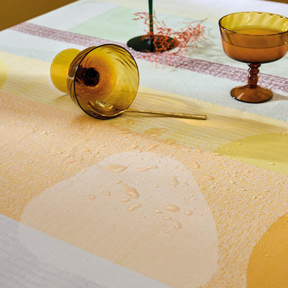 Mille Galets Terre Cuite Coated Tablecloth, water-resistant cotton jacquard with yellow, brown, and green circular pebble motif.