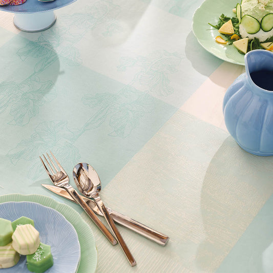 Closeup view of the Mille Iris D'Eau Aqua Tablecloth, blue and white iris floral madras plaid on cotton jacquard, set for a garden-inspired dining scene.