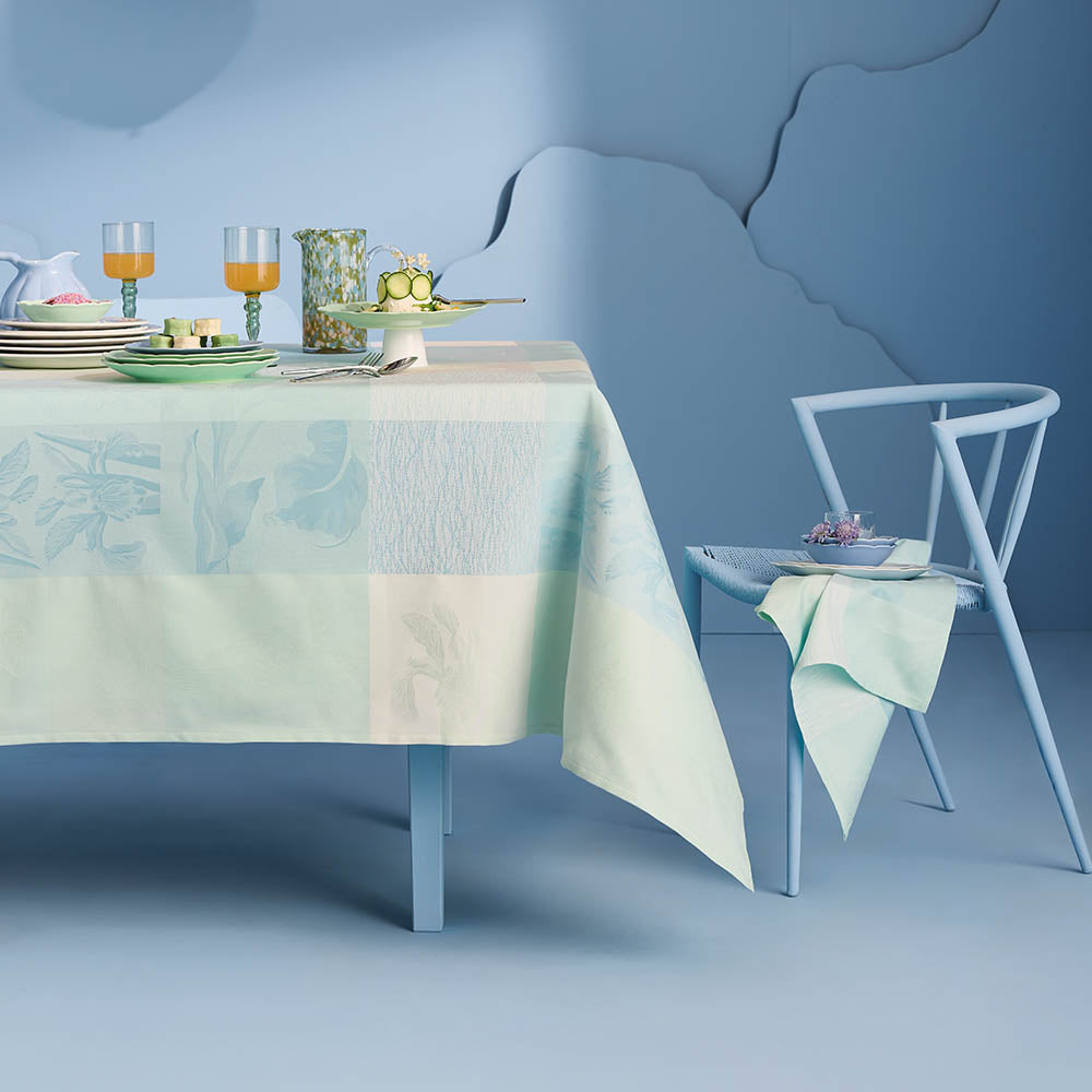 Mille Iris D'Eau Aqua Tablecloth, blue and white iris floral madras plaid on cotton jacquard set in a powder blue room.