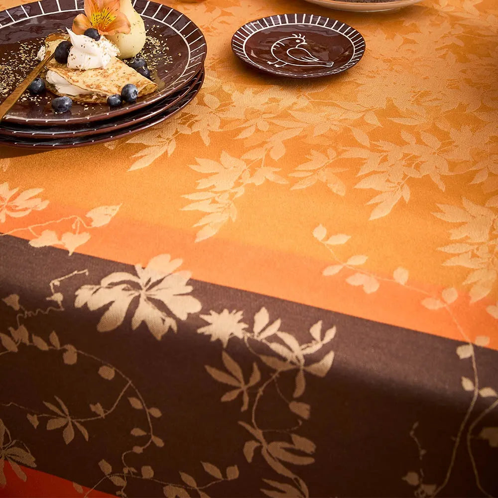 Close-up of Mille Lierres Automne cotton jacquard tablecloth in orange and brown.
