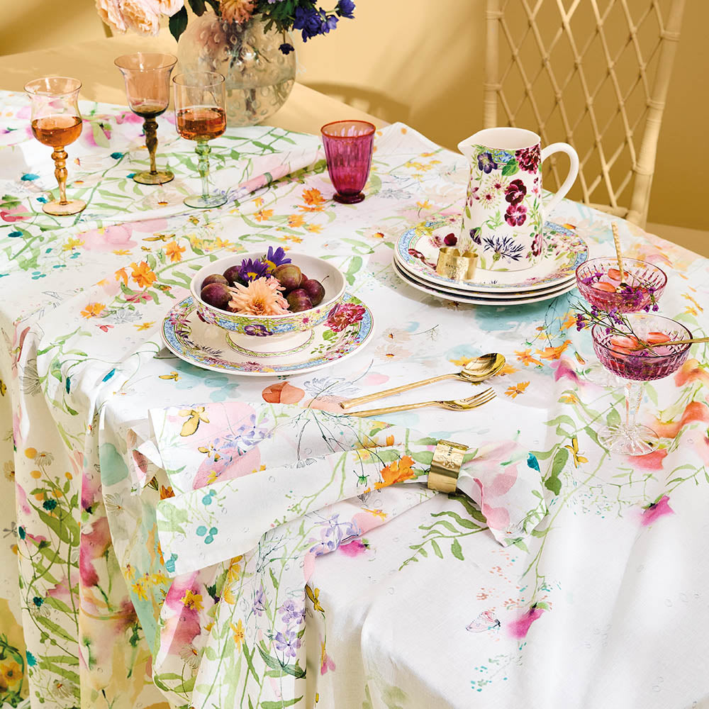 Rosee Du Matin Printemps Tablecloth, pink and green watercolor floral print on cotton-linen blend, set with floral dinnerware and pink glassware.