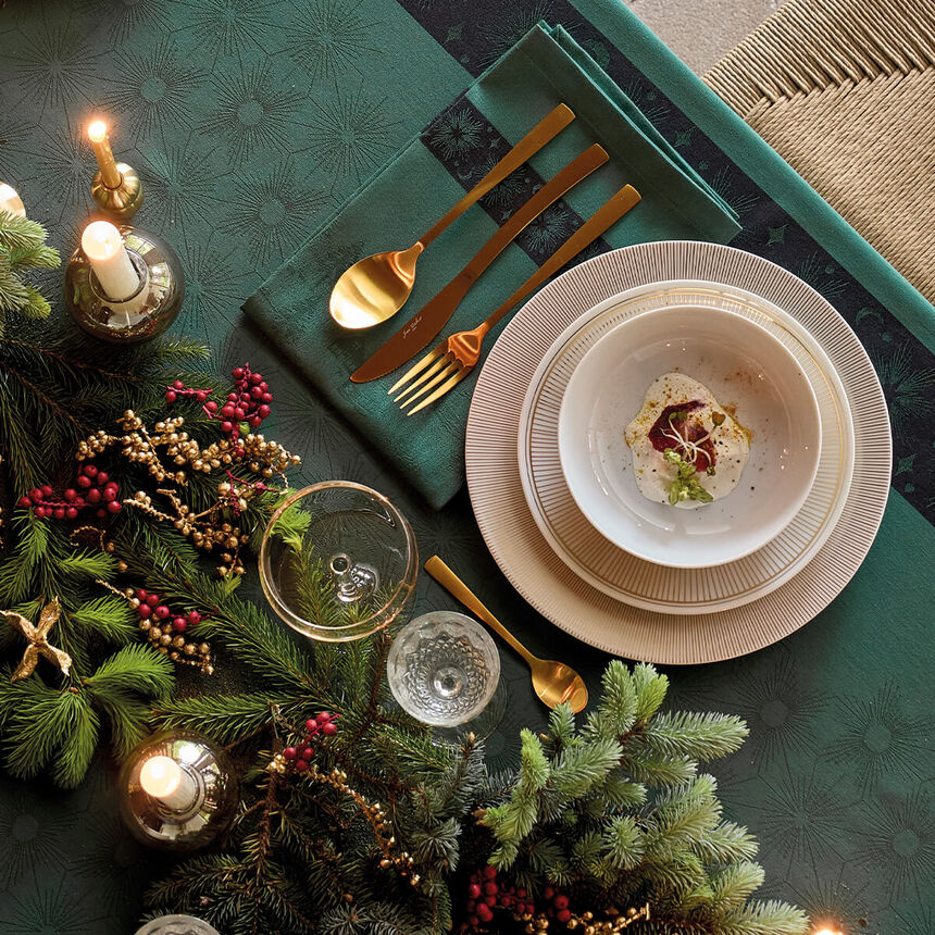 Aerial view of green Sous Les Étoiles French cotton jacquard napkin styled on a holiday place setting.