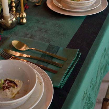 A styled dining table setting featuring a teal damask tablecloth with a central black stripe, accompanied by matching teal napkins, gold flatware, white ceramic plates, and candles.