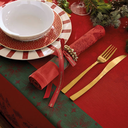 Red Sous Les Étoiles French cotton jacquard napkin tied with a red ribbon on a holiday place setting.
