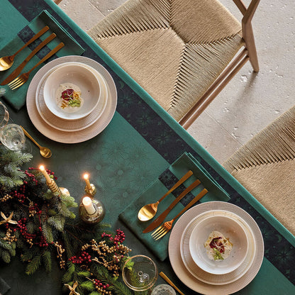 Aerial view of Green Sous Les Étoiles French cotton jacquard tablecloth draped on a dining table with Christmas styled table settings.
