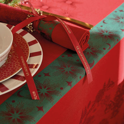 Close-up of red Sous Les Étoiles jacquard tablecloth with matching folded napkin tied in ribbon.