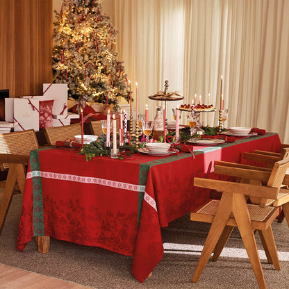 Red Sous Les Étoiles French cotton jacquard tablecloth styled on a festive holiday dining table with a Christmas tree.