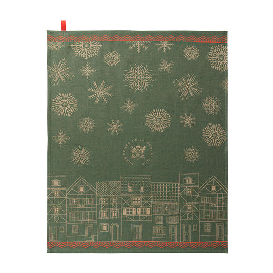 A forest green dishtowel featuring a festive Christmas design with gold snowflakes, a row of gold houses along the bottom, and red decorative borders at the top and bottom.