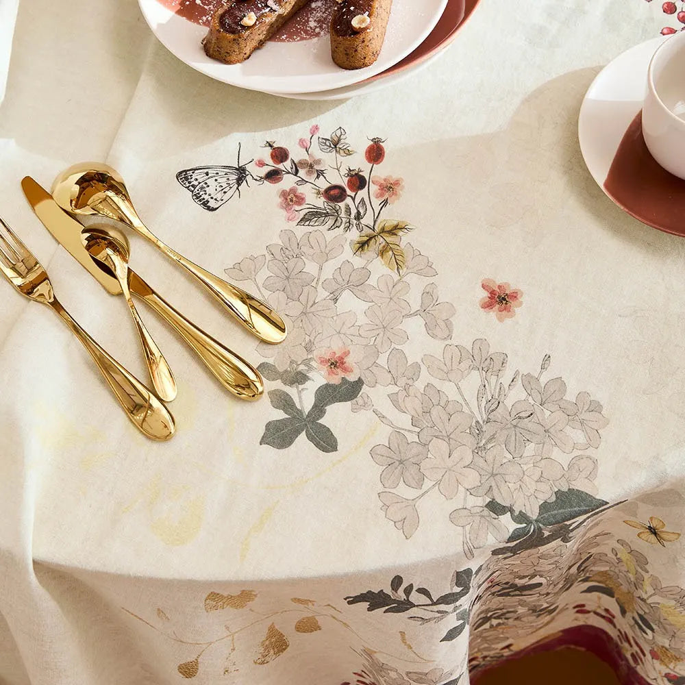 Close-up of a delicate, vintage style illustration of butterflies, cranberries and flowers on a printed cotton-linen tablecloth