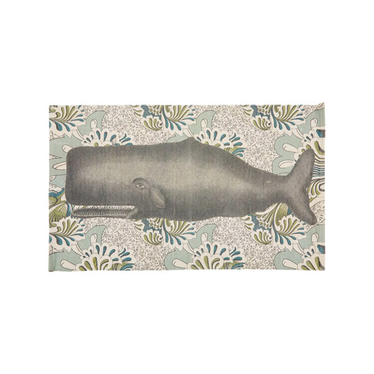 A top-down view of a rectangular, hand-loomed cream cotton bath rug featuring a large-scale illustration of a majestic charcoal gray whale set against an intricate, vintage botanical floral pattern background in soft sage green and denim blue tones.