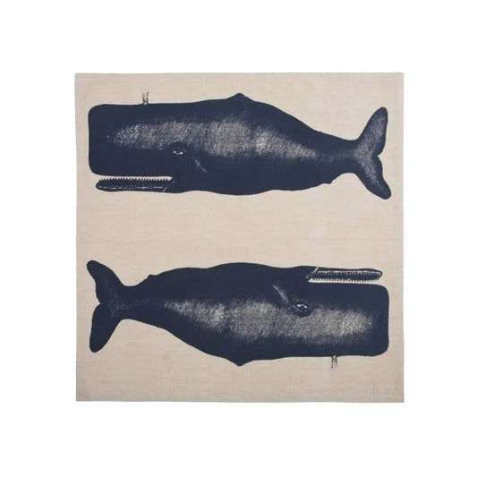 A flat-lay view of a square, off-white cotton dinner napkin featuring two large, detailed illustrations of mirror-image whales screen-printed in deep navy blue ink.
